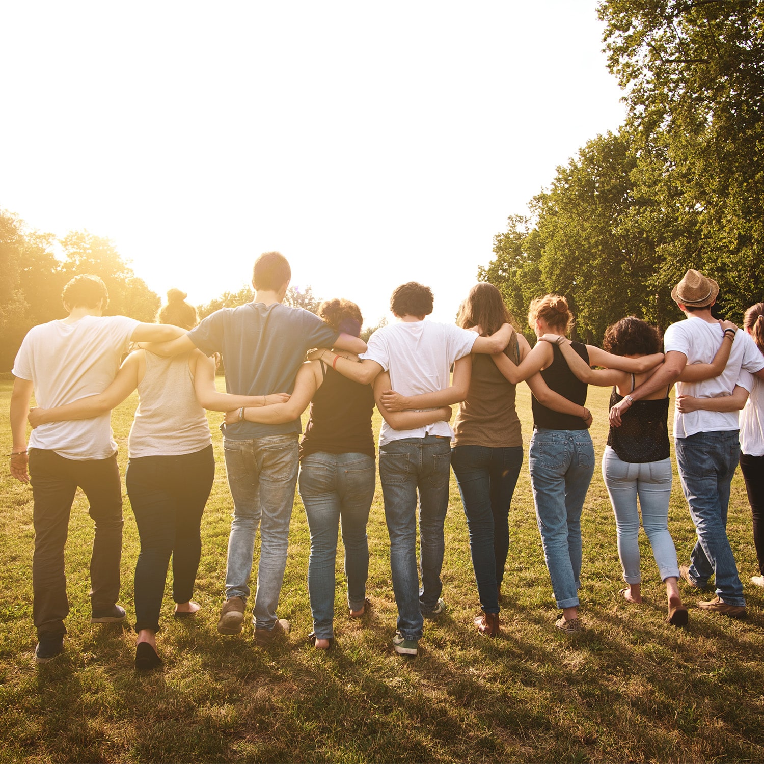 Auf dem Bild geht eine Gruppe von 10 Menschen in einer Reihe gemeinsam den Sonnenuntergang entgegen.